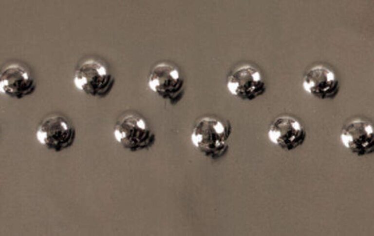 Close-up of a metal surface with two rows of shiny rivets