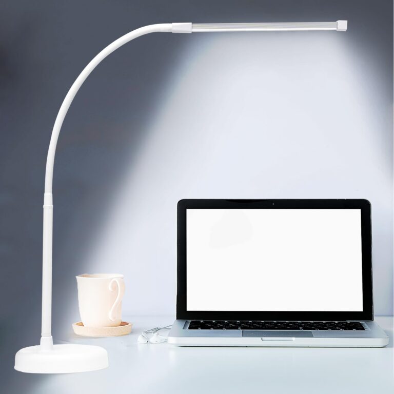 White desk lamp, laptop, cup, and earbuds on a white desk